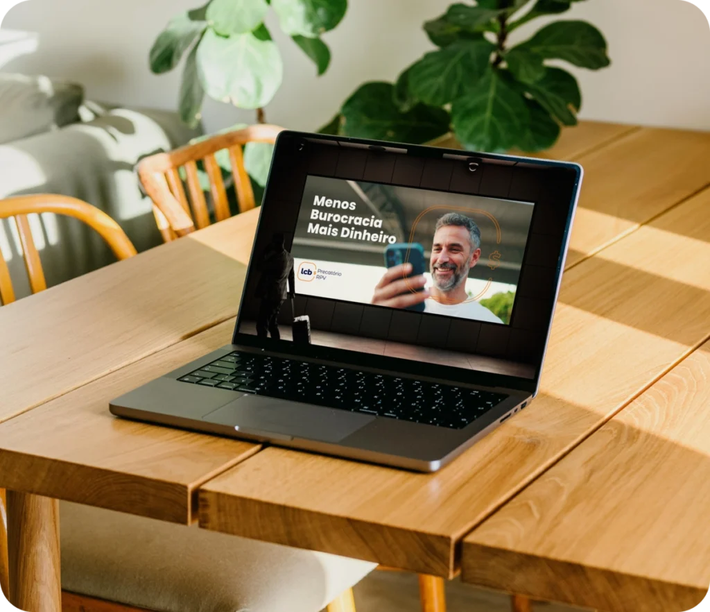 Laptop aberto exibindo vídeo "Menos Burocracia Mais Dinheiro" do LCbank